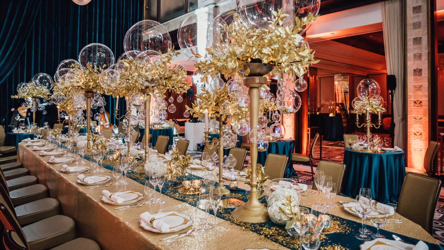 Long gold table with turquoise runner and gold candelabras with gold trim and glass balls