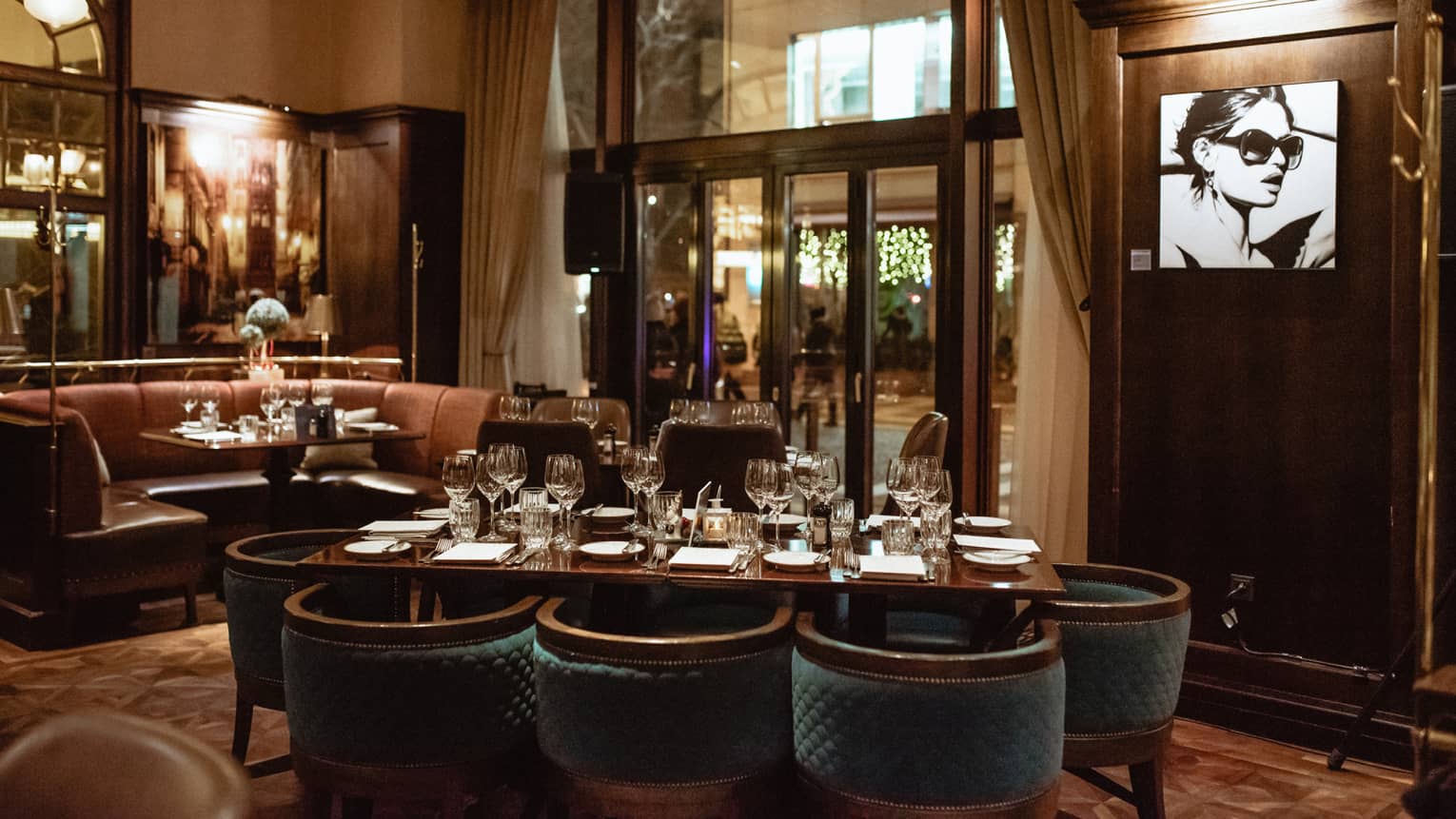 Dark restaurant with banquette seating, table and chairs, outside nighttime view