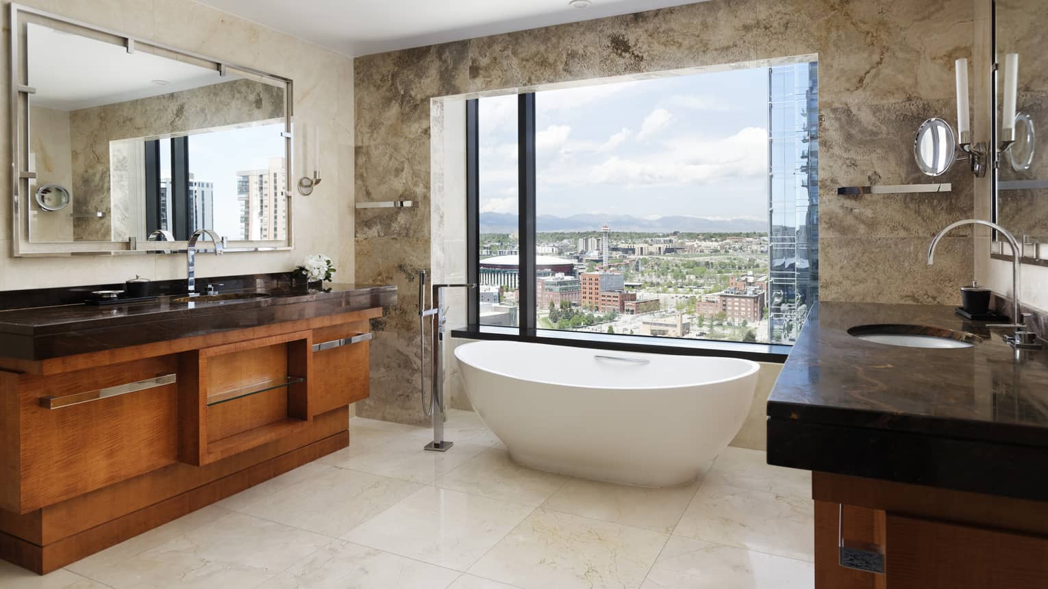 A bathroom with a deep bathtub, large window, and wood and dark stone sink.