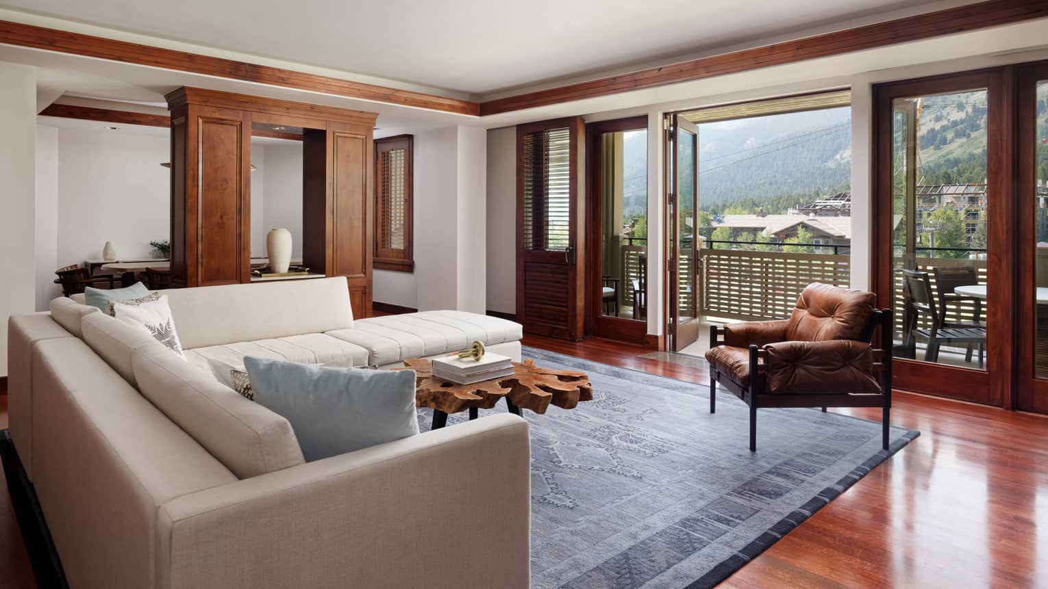 Living room with cream L-shaped sofa, leather arm chair and views of mountains