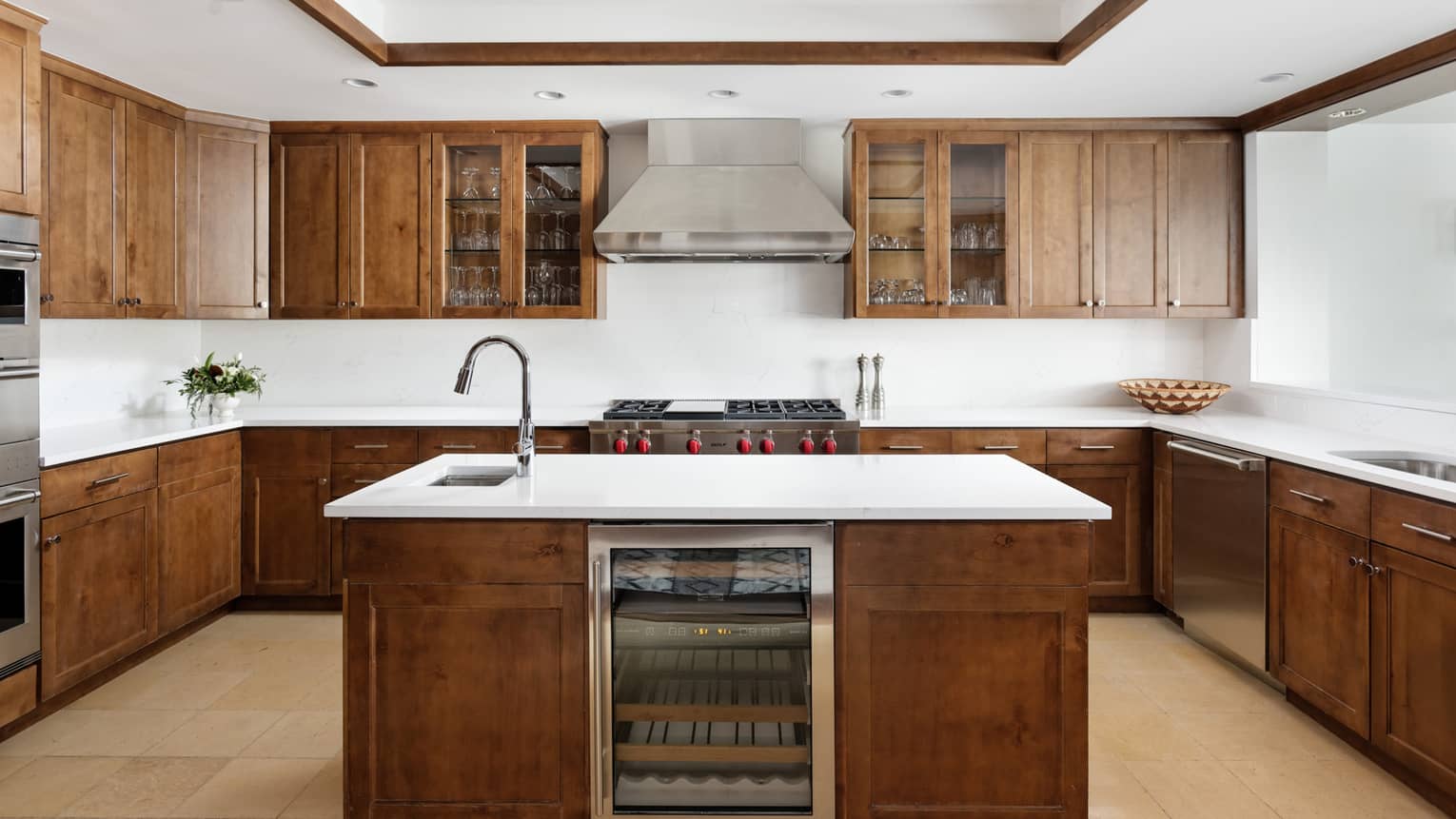 Kitchen with dark wood cupboards and white countertops, island with built-in wine fridge and sink