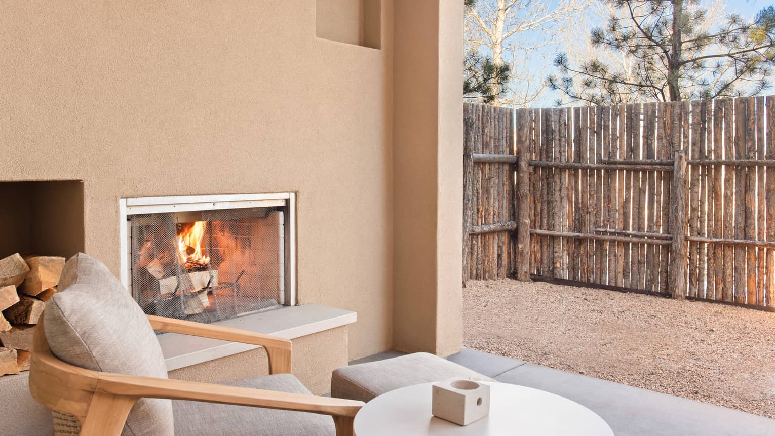 Fireplace and lounge chair on a private patio of Casita Room at Four Seasons Resort Santa Fe