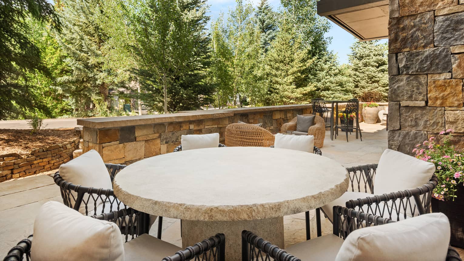 A large stone table on a patio with many chairs.