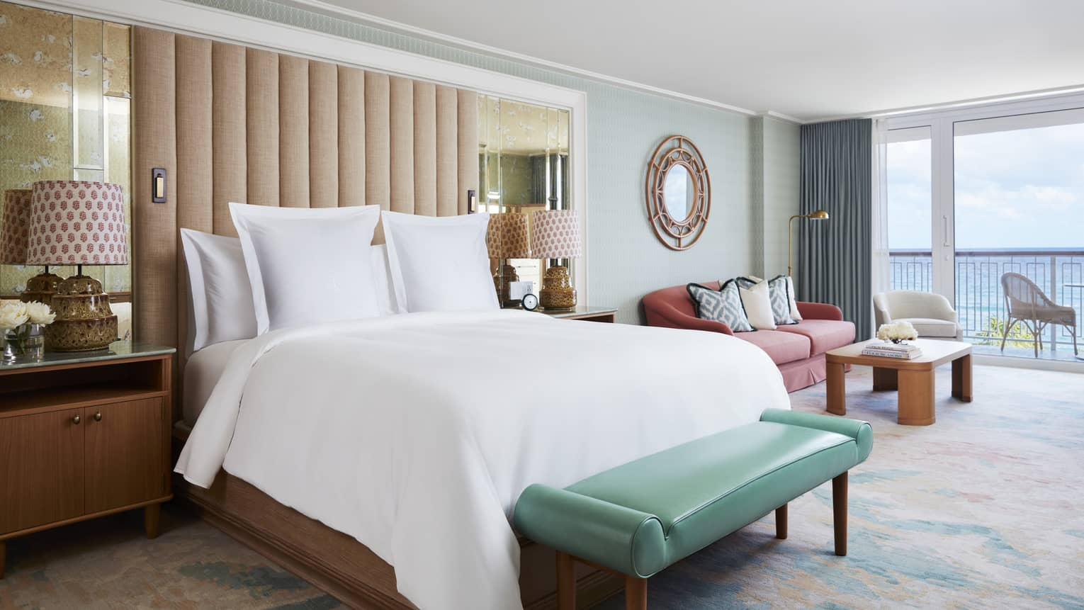 Ocean View Studio Suite bed and teal leather bench by seating area, balcony door