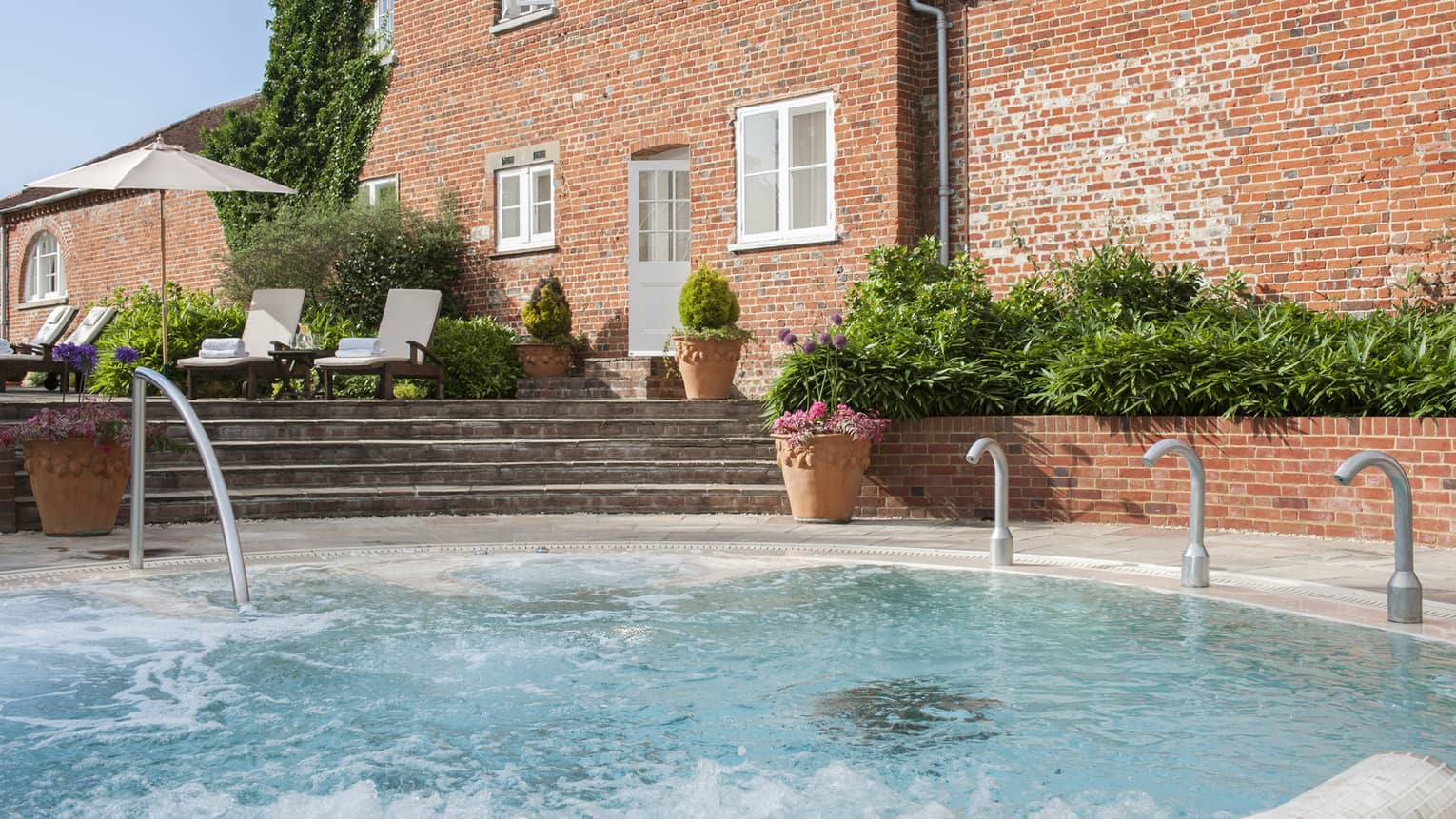 Outdoor swimming pool and steps under red brick hotel exterior on sunny day