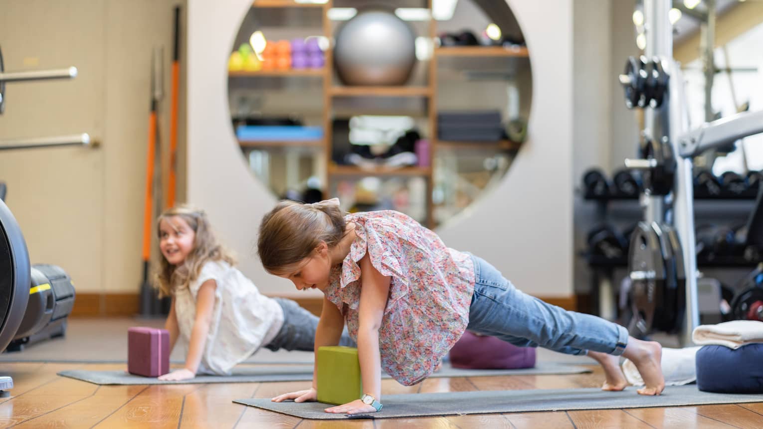 Two girls in downward dog yoga pose over yoga blocks and mats