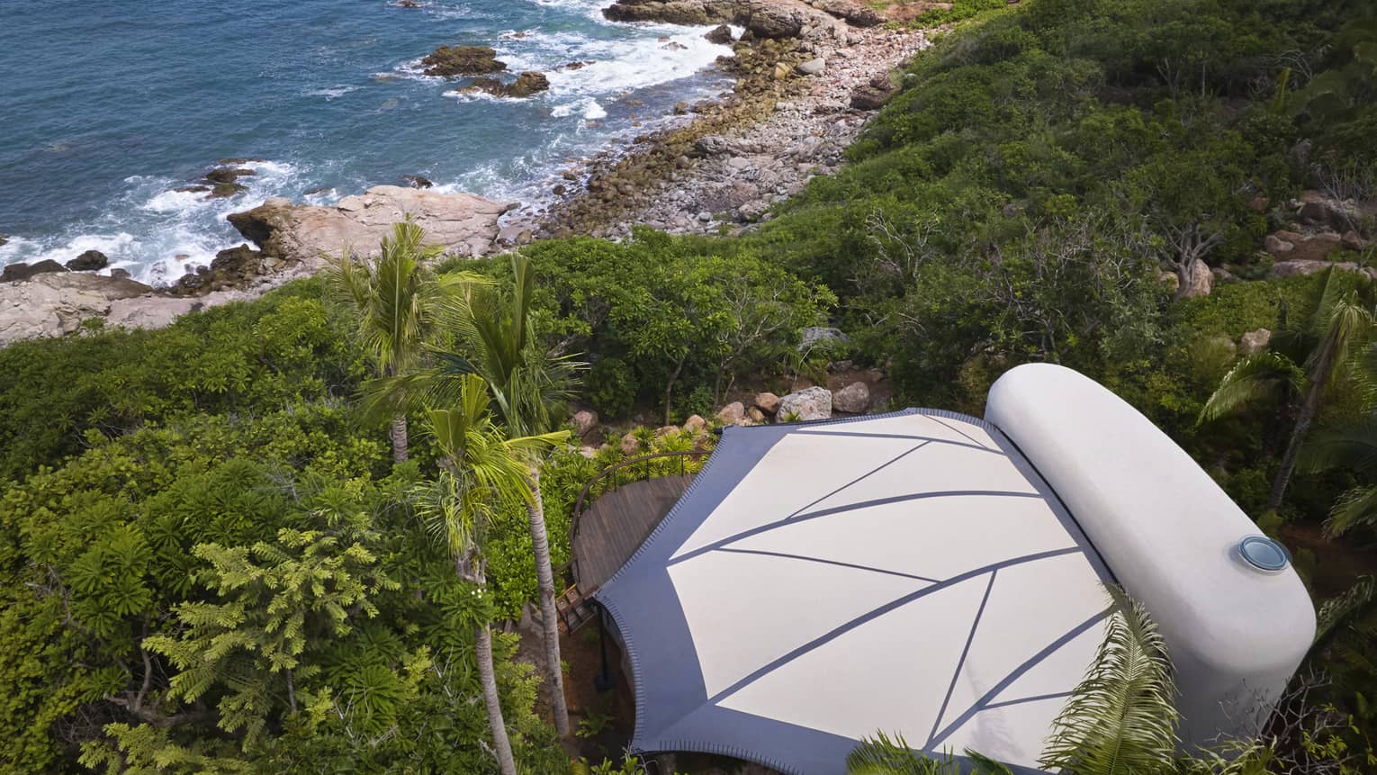 Aerial view of a private luxury tent nestled in the jungle, next to the beach