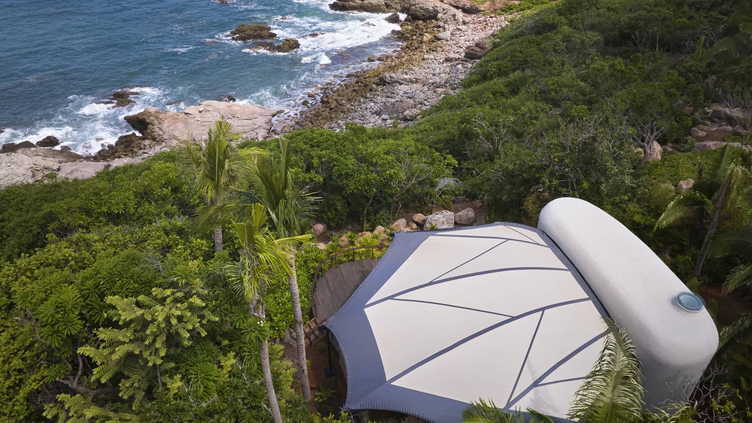 Aerial view of a private luxury tent nestled in the jungle, next to the beach