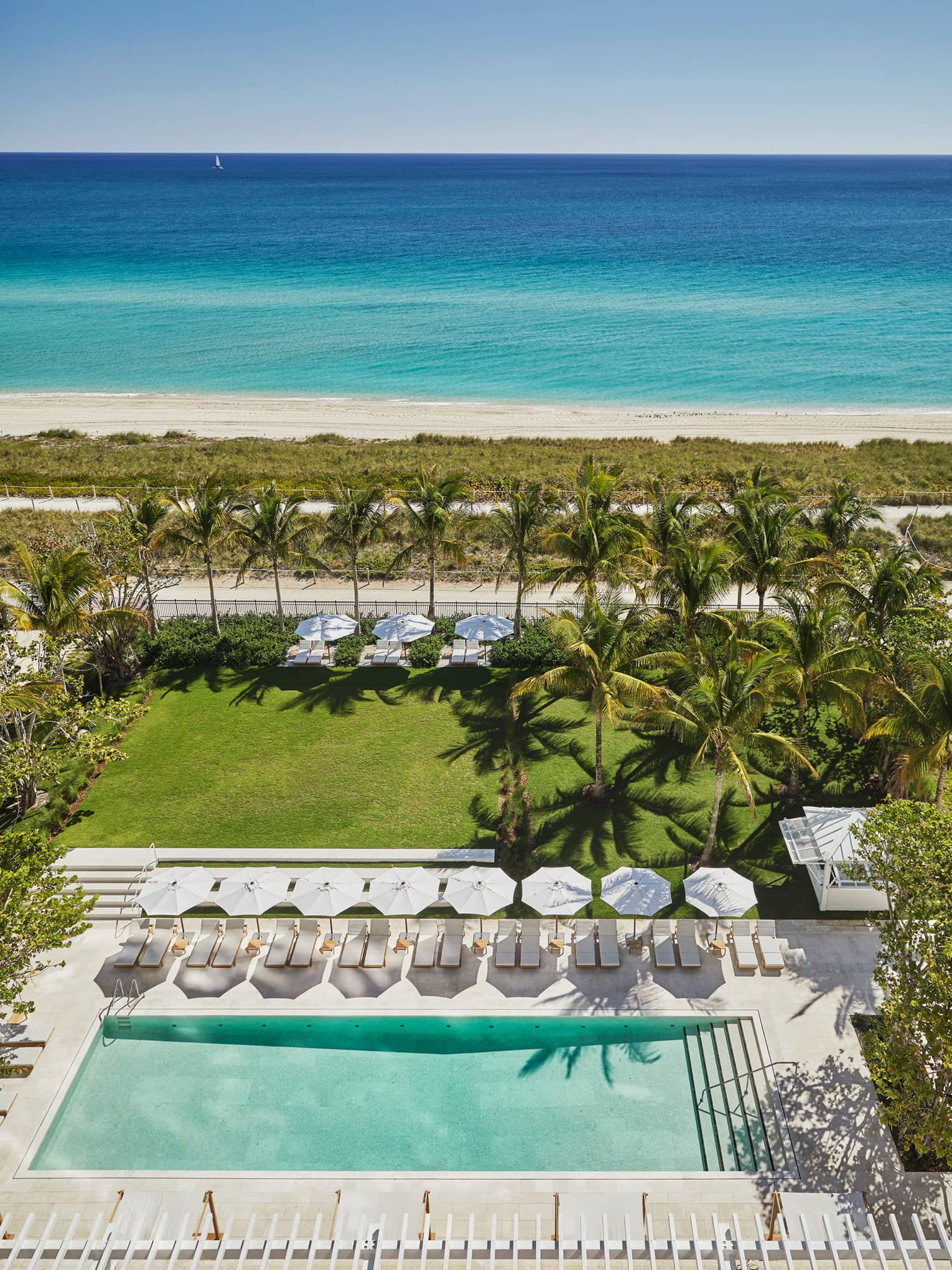 Aerial view of resort lawns, adult pool and lounge chairs, beach and ocean in background