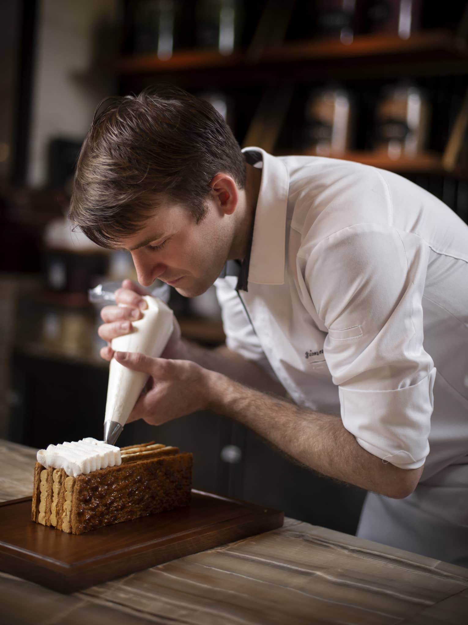 Executive Pastry Chef Jimmy Boulay pipes cream onto mille-feuille with pastry bag