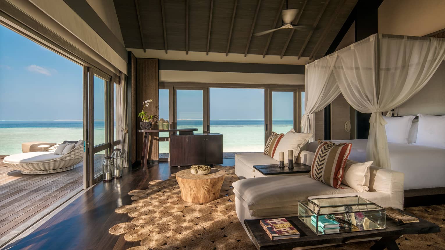 Three-Bedroom Beach Villa canopy bed. chaise lounge chairs across from open sliding doors to patio