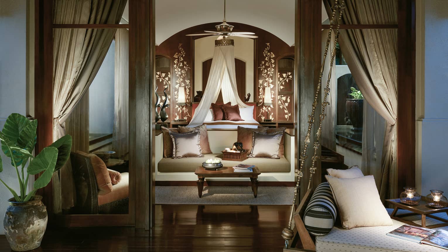 View from doorway into elegant Pool Villa with loveseat and brown silk pillows, white canopy over bed