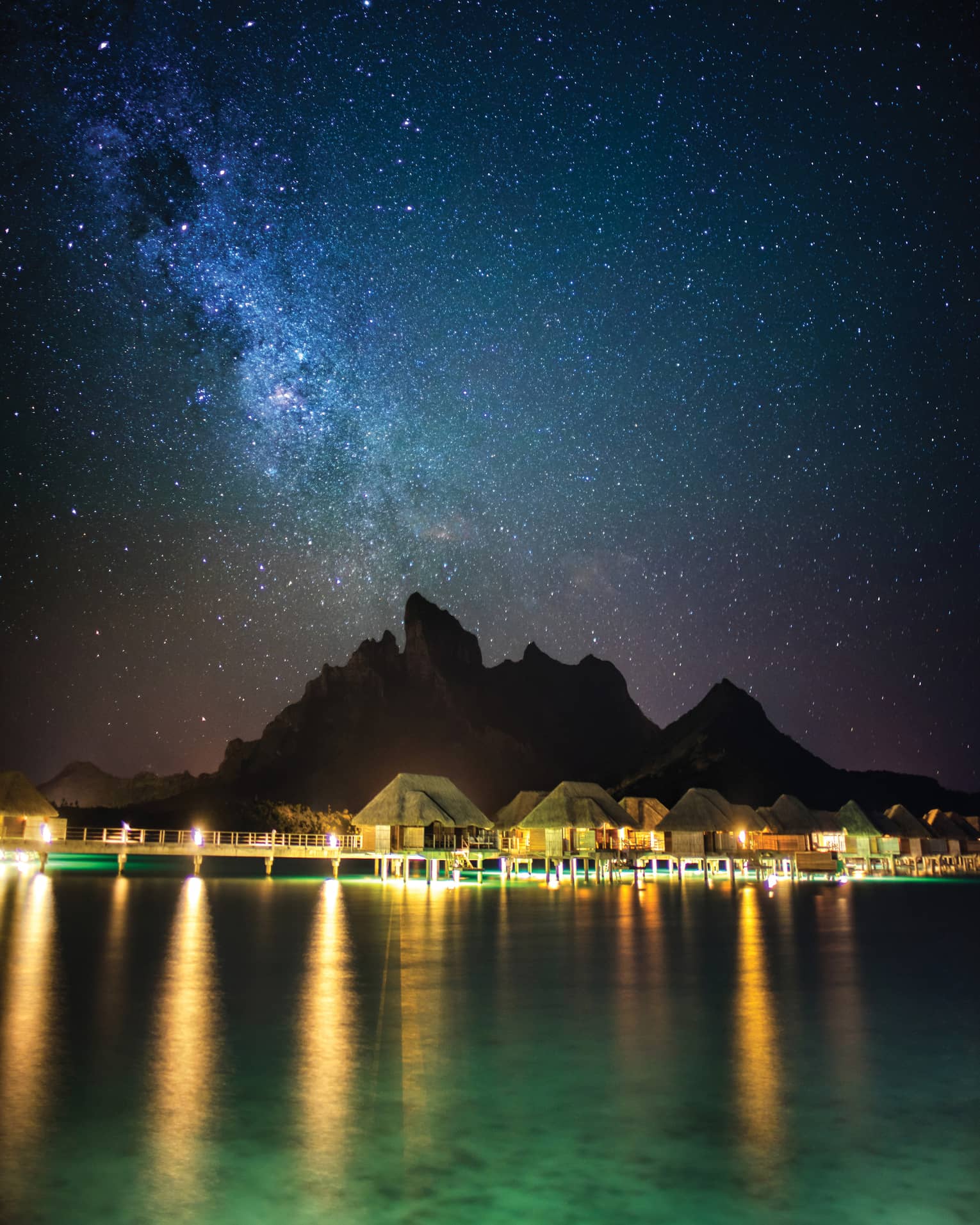 Illuminated Four Seasons Resort Bora Bora beneath a blanket of stars at night