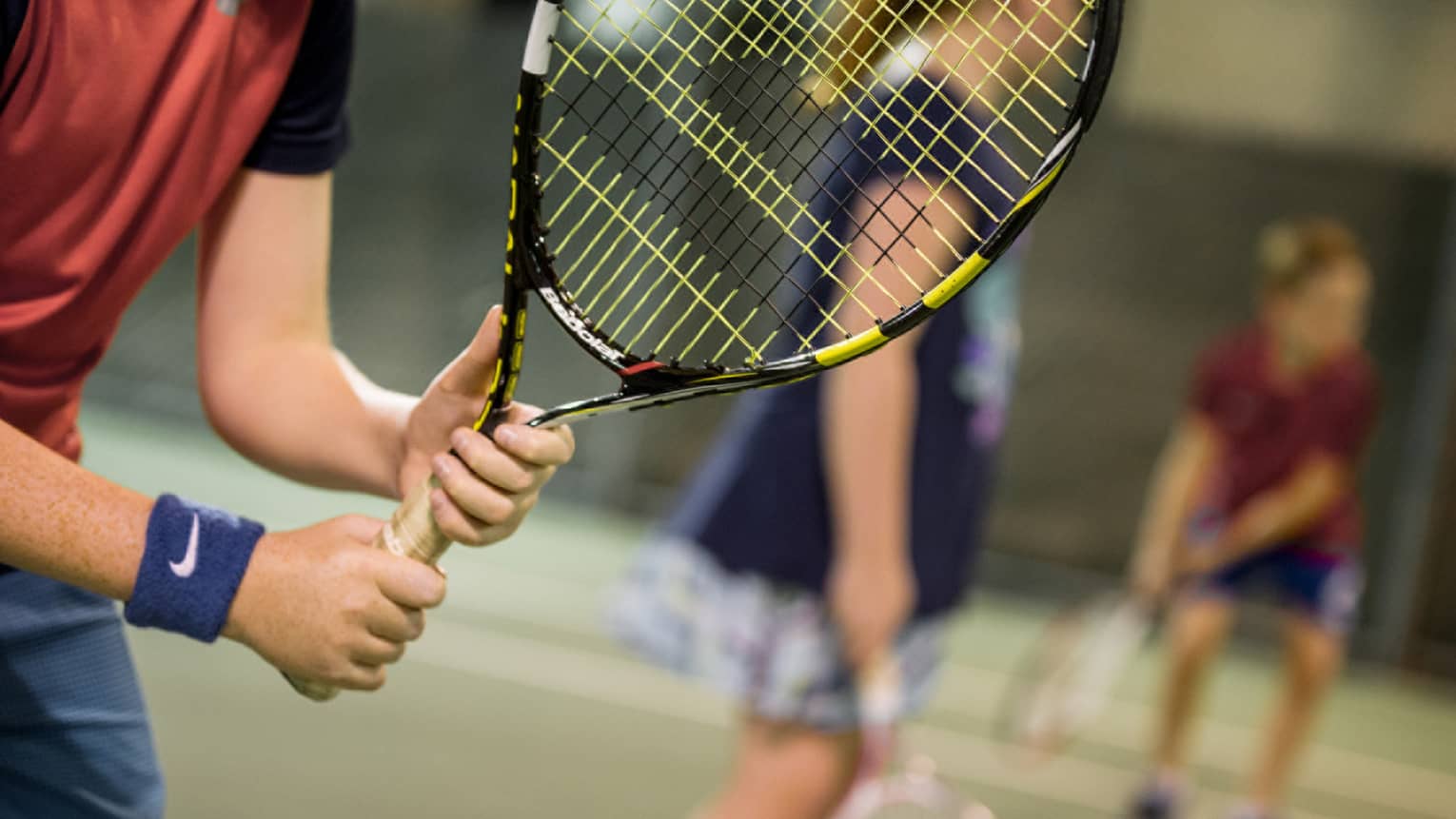 Close-up of hands holding yellow-and-black tennis racket