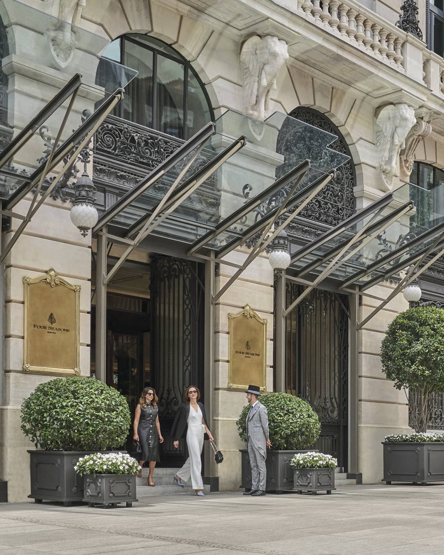Two guests walking out of the Four Seasons Hotel Madrid entrance