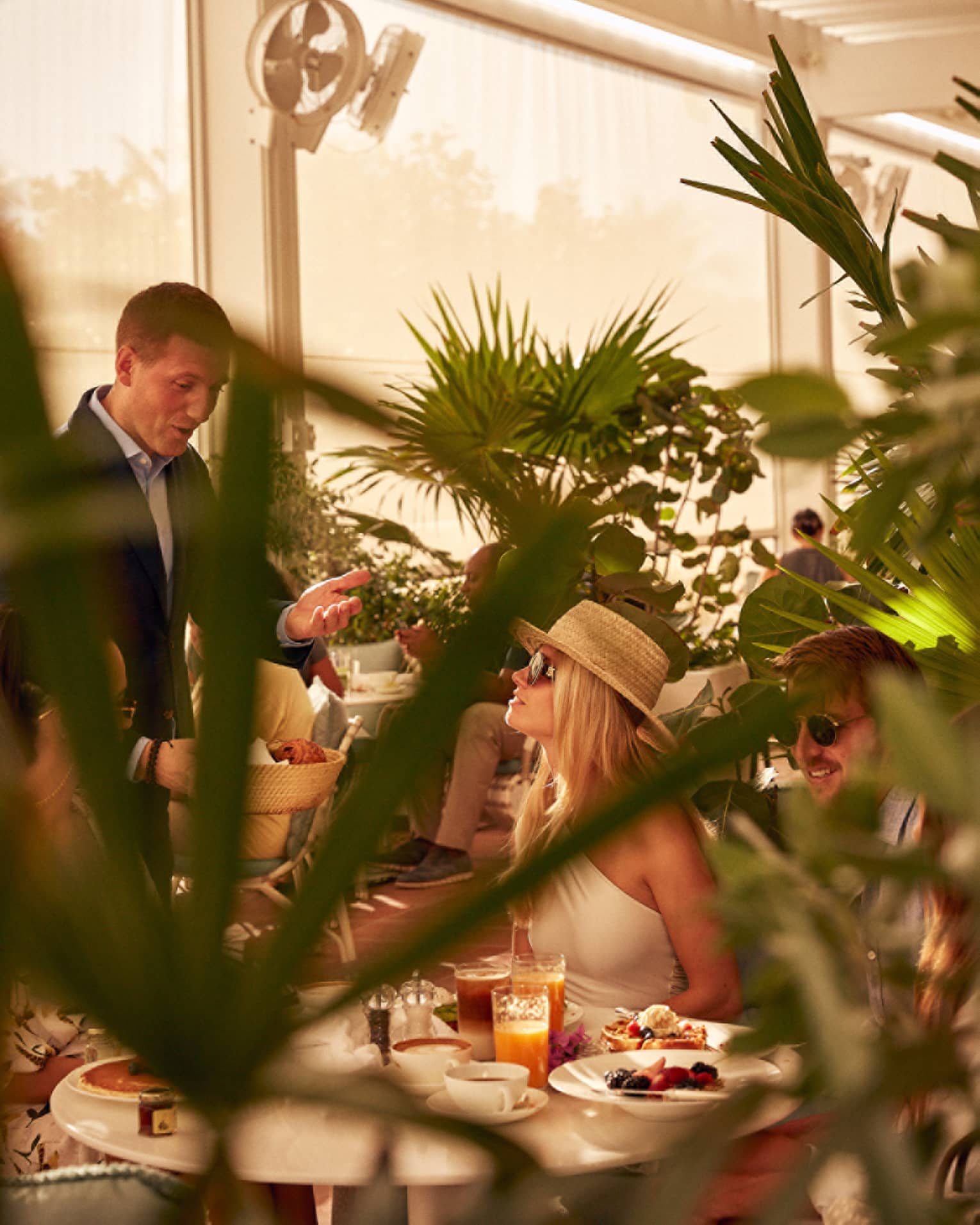 A woman being served food in a covered eating area with plants.