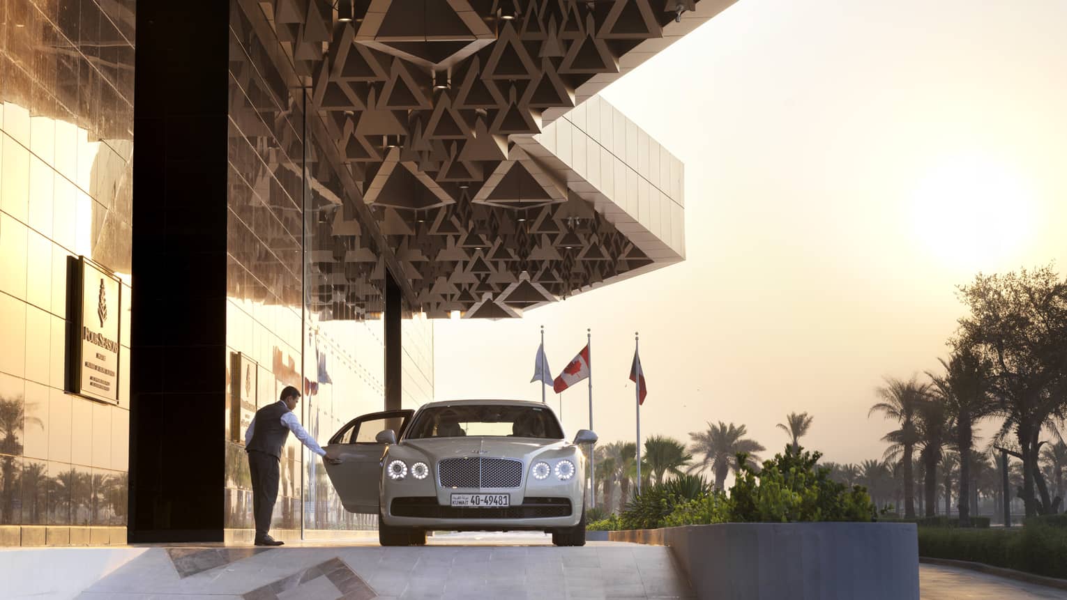 Four Seasons Hotel Kuwait doorman opens luxury car door near entrance 