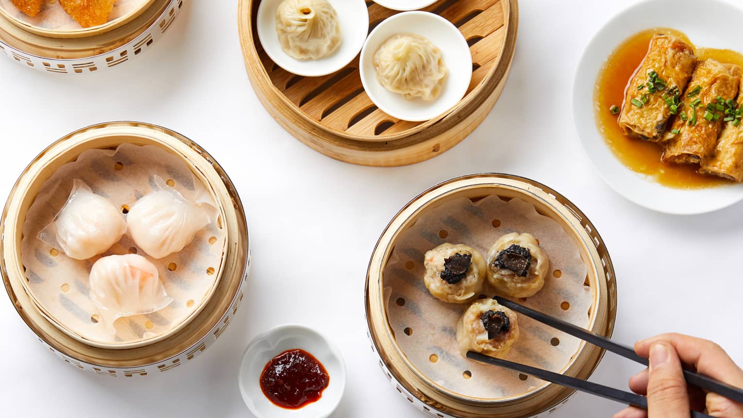 Aerial shot of Dim Sum selection, man reaching for dumplings steamer basket with chopsticks