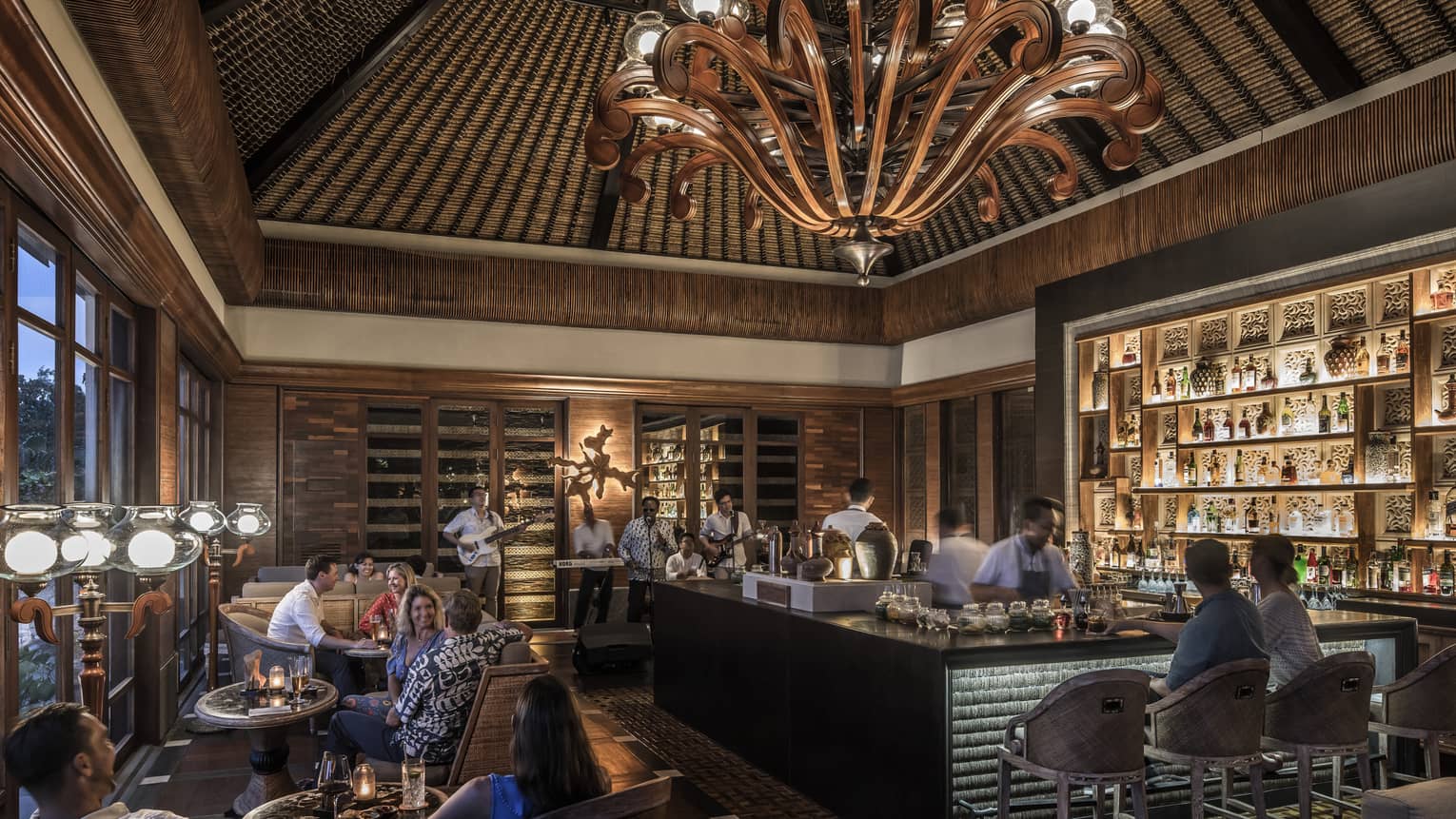 Sundara cocktail lounge, large wood chandelier over guests, bar with lights