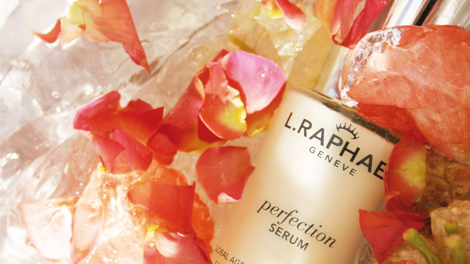 Close-up of bottle of L.RAPHAEL facial serum surrounded by fresh pink flower petals