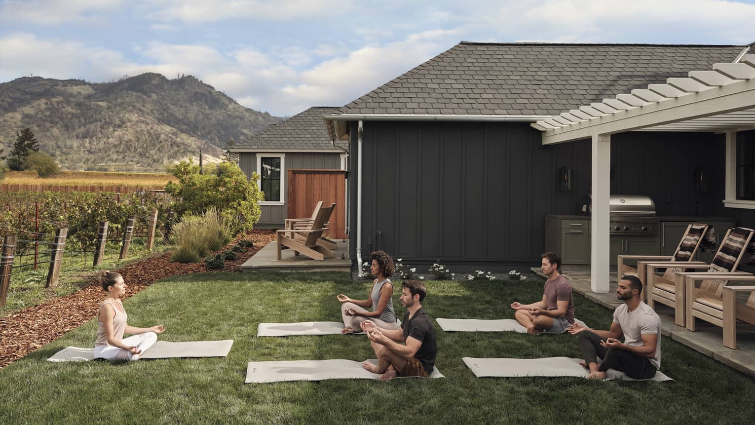 Guests participating in an outdoor group yoga class, with mountains in background