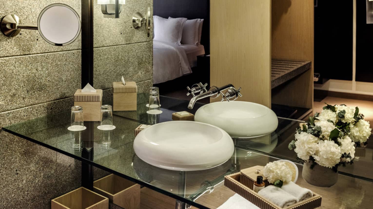 In-room bathroom featuring a glass vanity with a white round porcelain sink