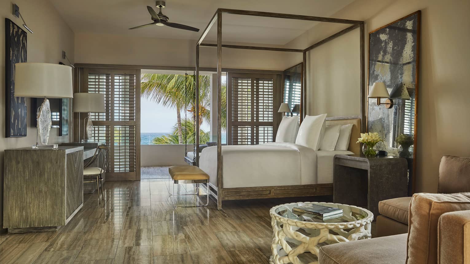 Three-Bedroom Beachfront Villa view from L-shaped sofa to canopy bed, tables with lamps, open patio shutters