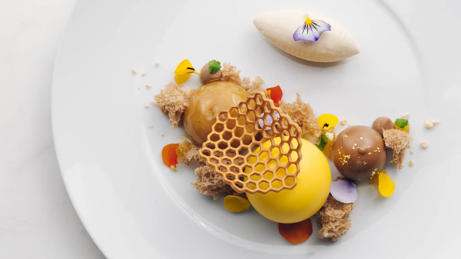 Wildflower Honey Cream with two spheres of brown ice cream and one of yellow ice cream, topped with honeycomb shape