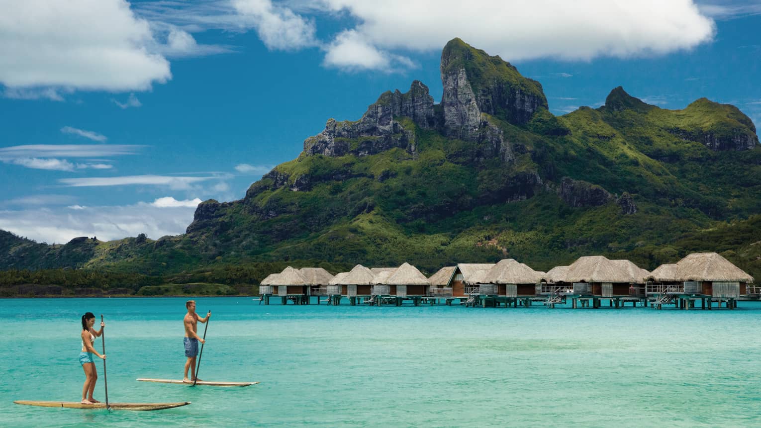 Two guests stand-up paddleboarding in a Bora Bora lagoon