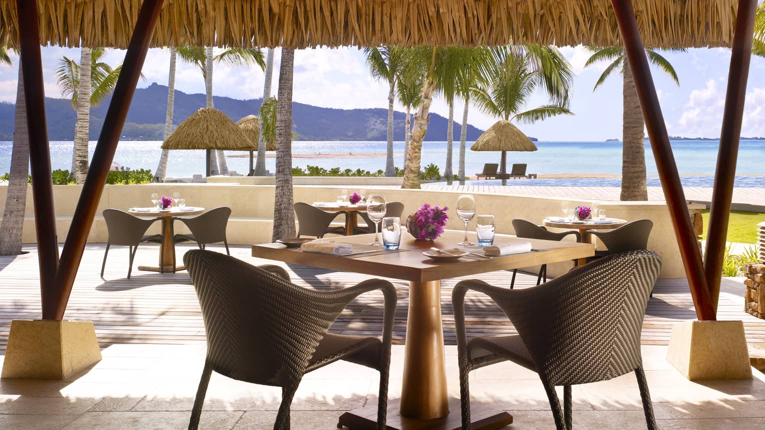 Tere Nui restaurant patio dining tables under flat thatched roof looking out at beach