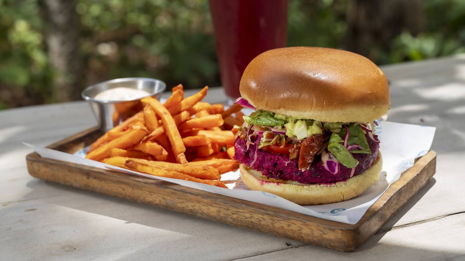Burger served with a side of fries on a rectangular wooden plate