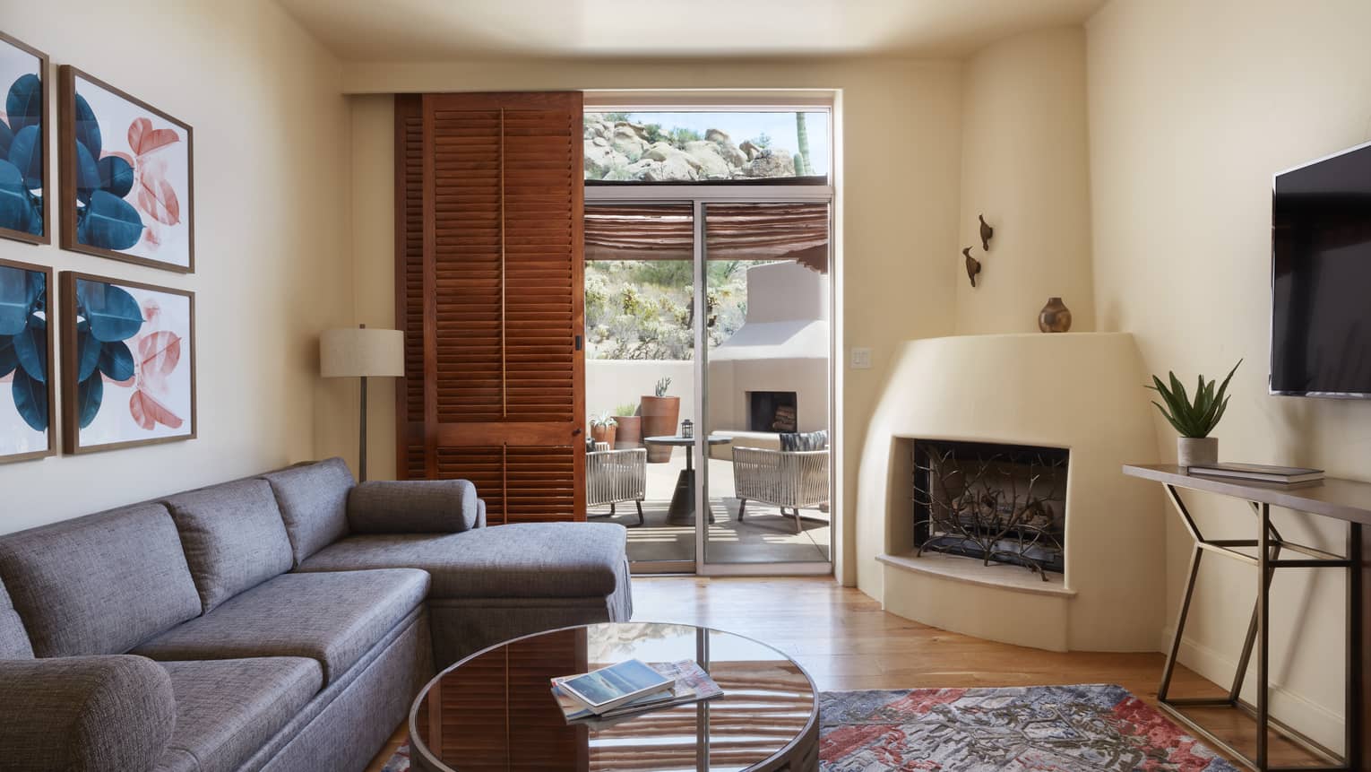 Living room with fireplace, sofa, coffee table, wooden door opening up to patio