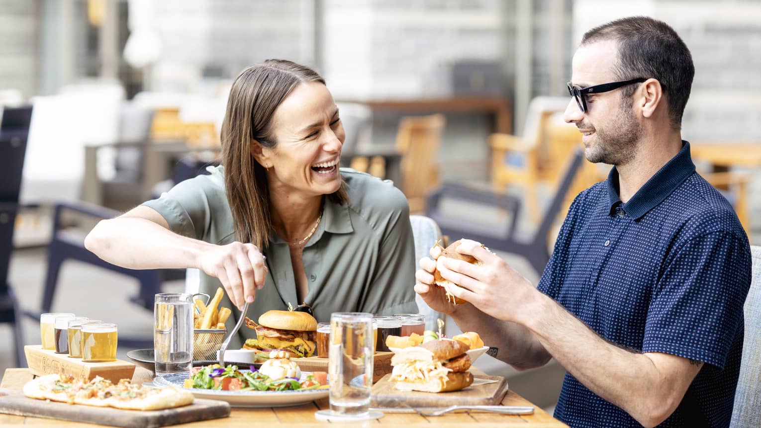 Laughing couple enjoys a meal on the outdoor terrace of a restaurant