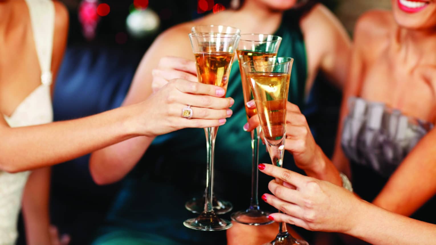 Close-up of women in evening gowns toasting with glasses of Champagne