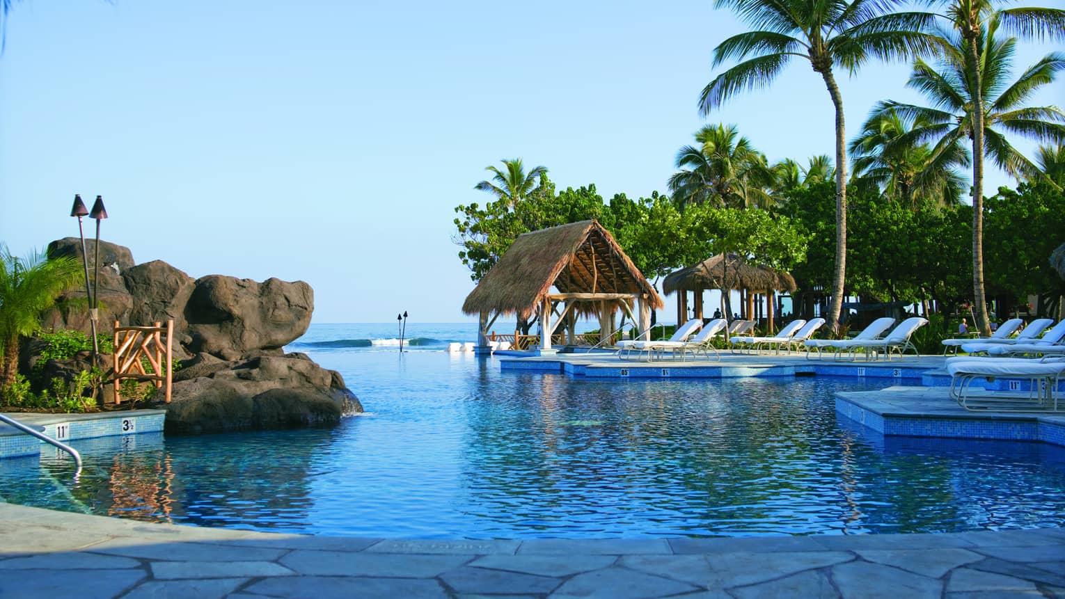 Sea Shell outdoor swimming pool with large boulders, thatched-roof hut