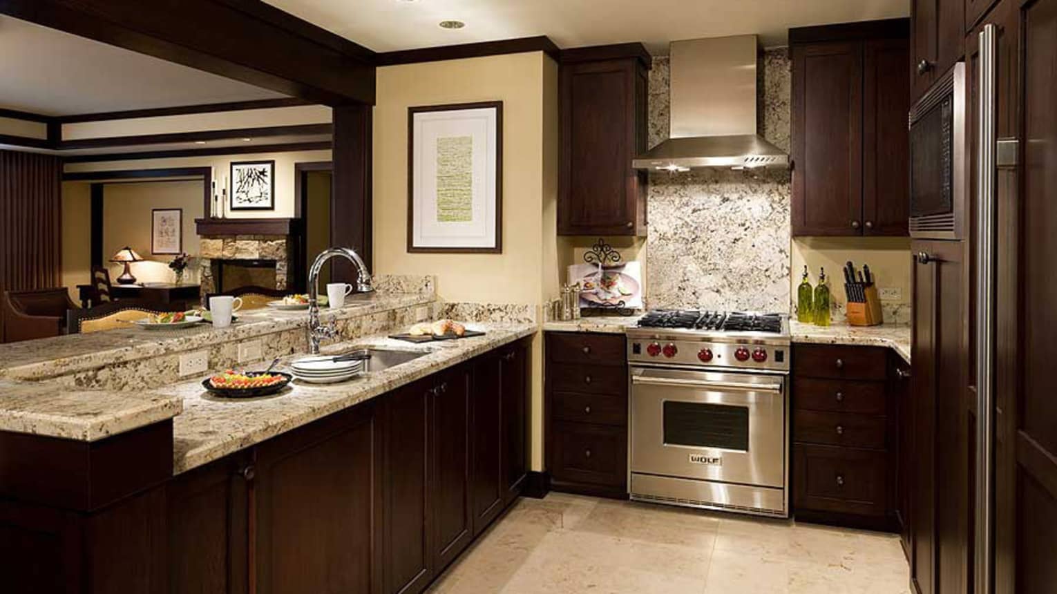 Kitchen with dark wood cupboards, marble counters, stainless steel stove