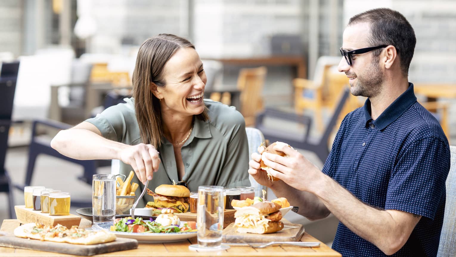 Laughing couple enjoys a meal on the outdoor terrace of a restaurant