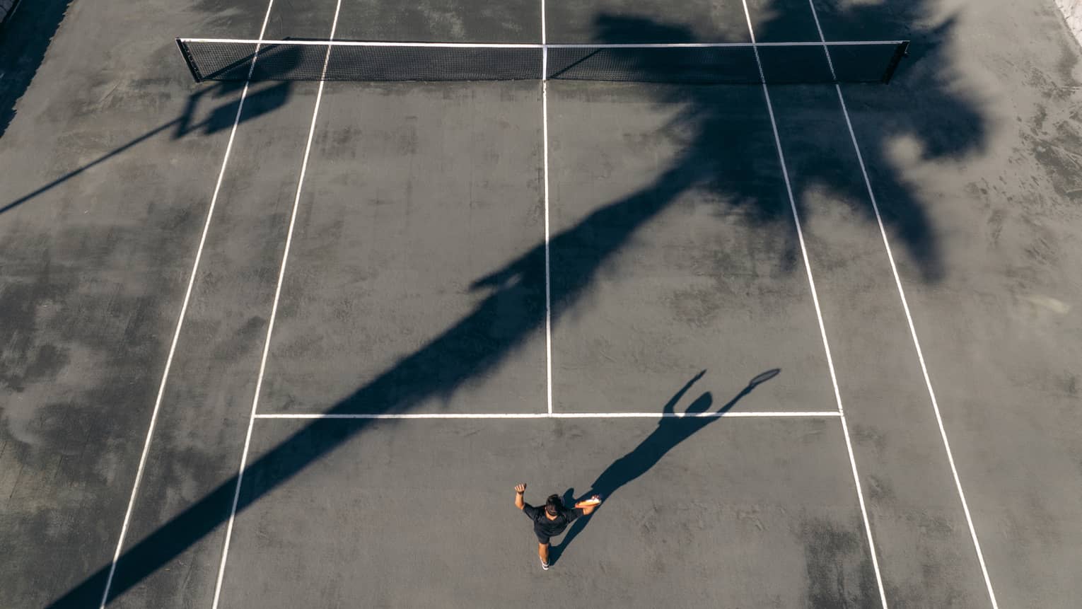 Aerial view of tennis player serving the ball on a clay court
