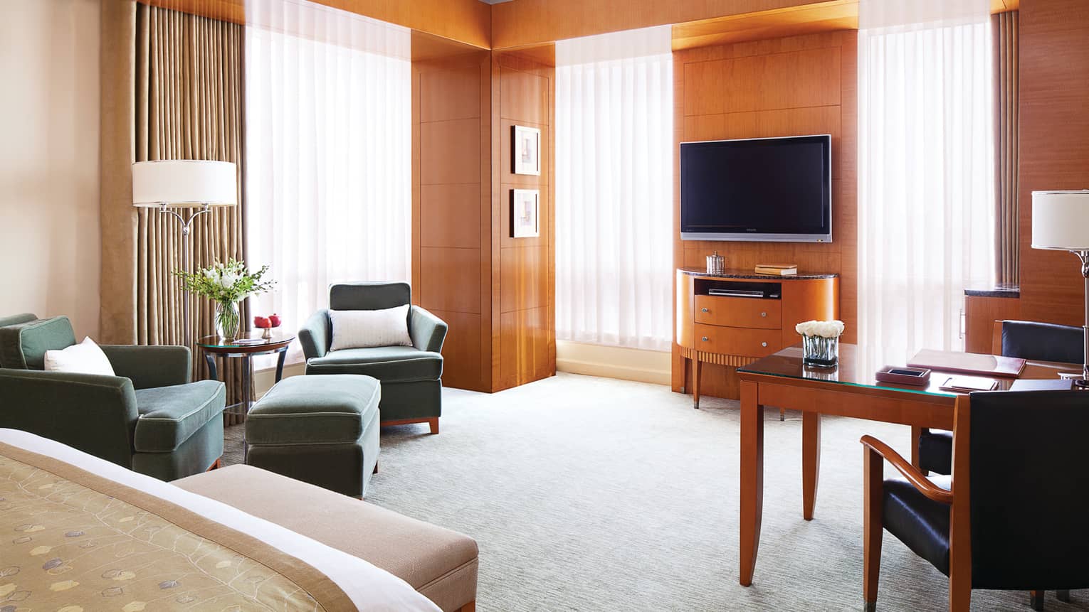 Executive Premier Room wood panel walls, sunny windows with sheer curtains, bed, TV, chairs
