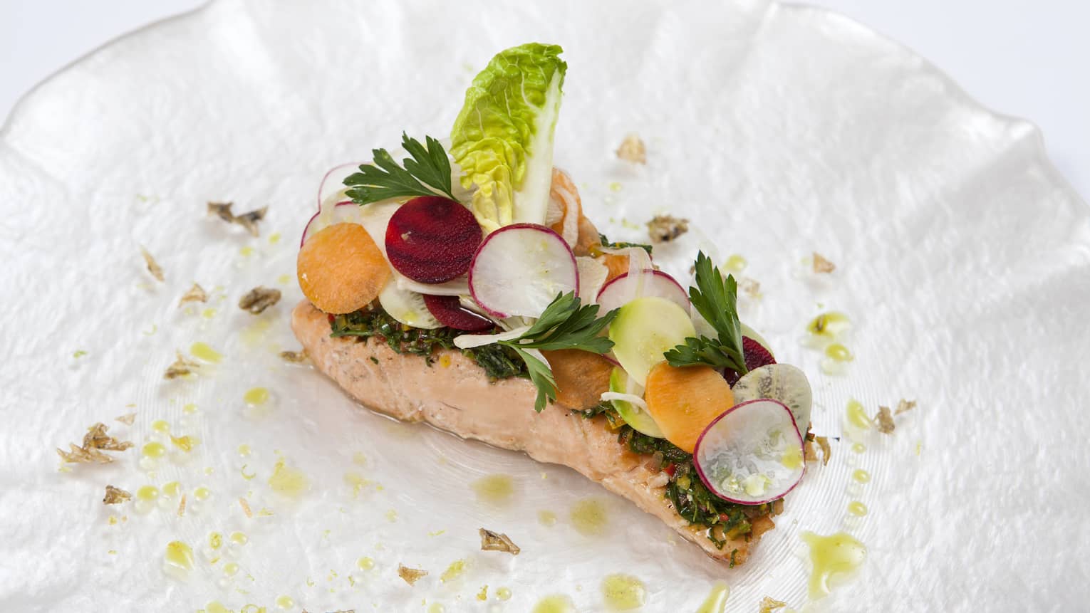 Seared salmon fillet topped with radish and lettuce garnish