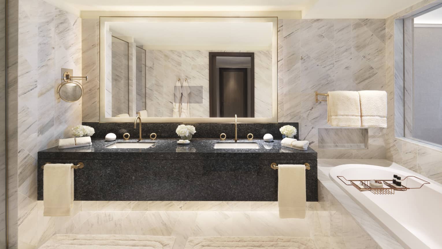 Marble bathroom with double vanity sinks and tub