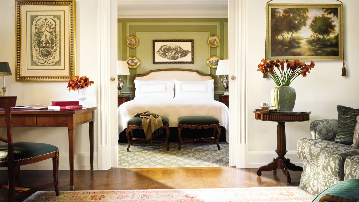 Four Seasons Executive Suite desk, chair by bedroom doorway, bed and scarf across green footstools