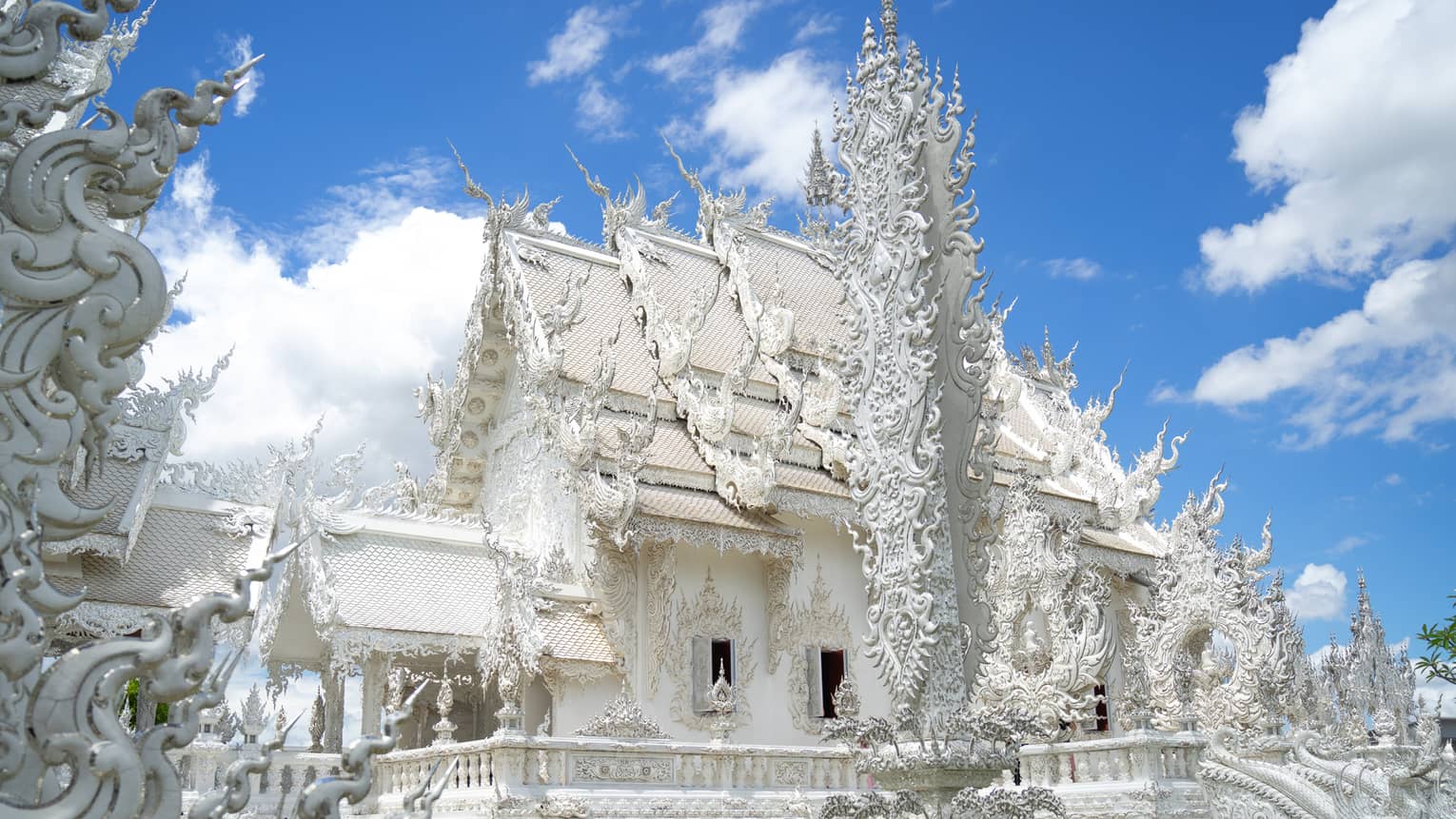 A stunning plaster temple with a gabled roof and intricate carvings, most in flame-shaped spikes jutting out from all sides.