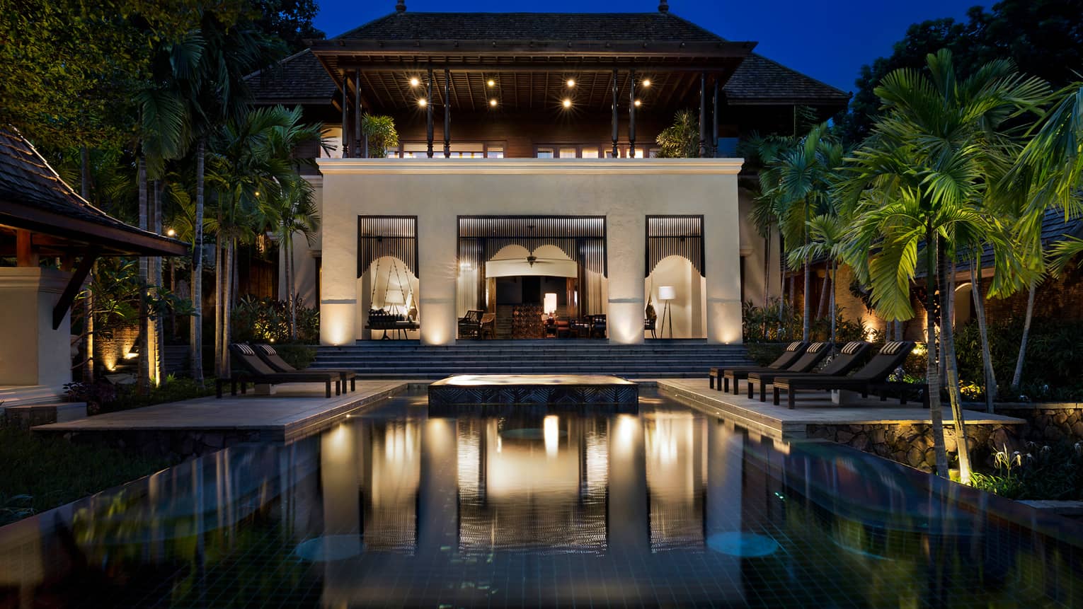 Large Four-Bedroom Residence Villa at night with lights, outdoor pool and palms 