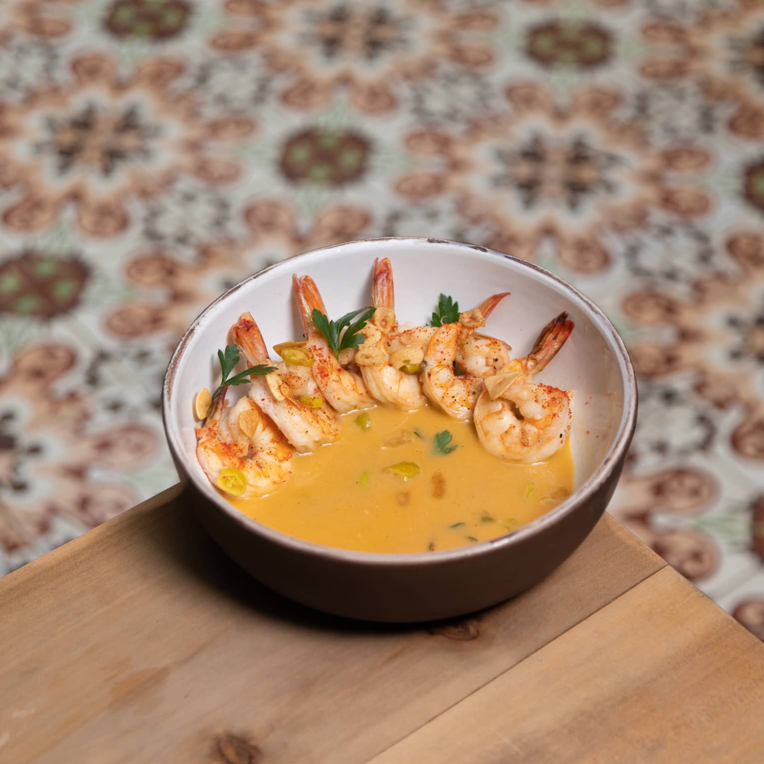 Shrimp in a yellow sauce served in a ceramic bowl.