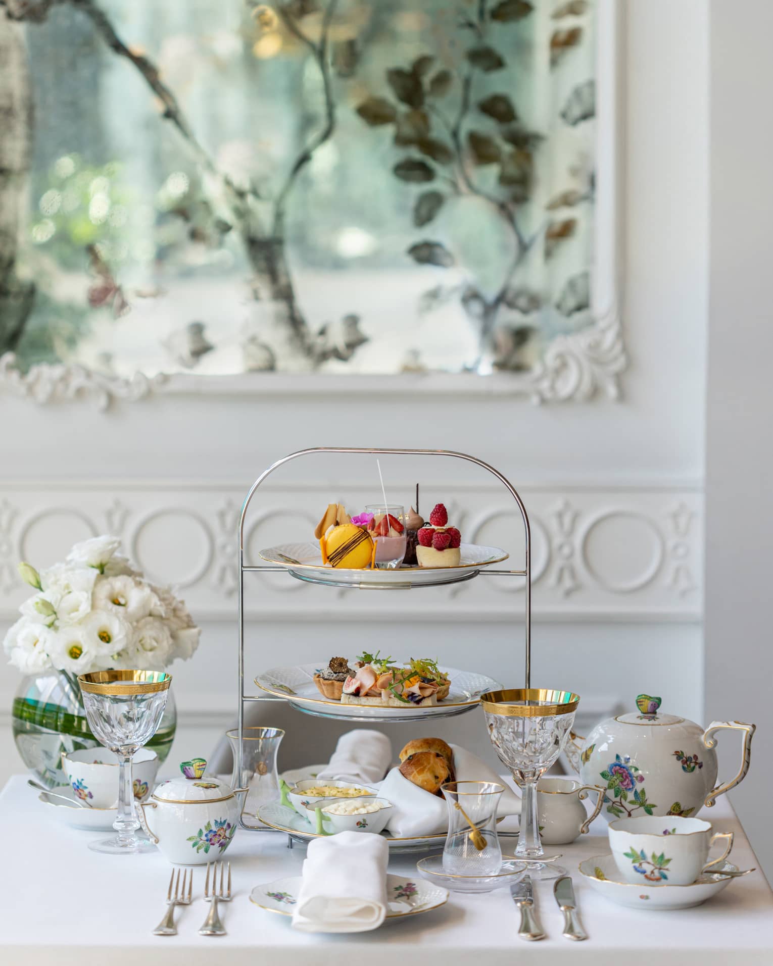 An afternoon tea set with pastries on trays and tea cups.