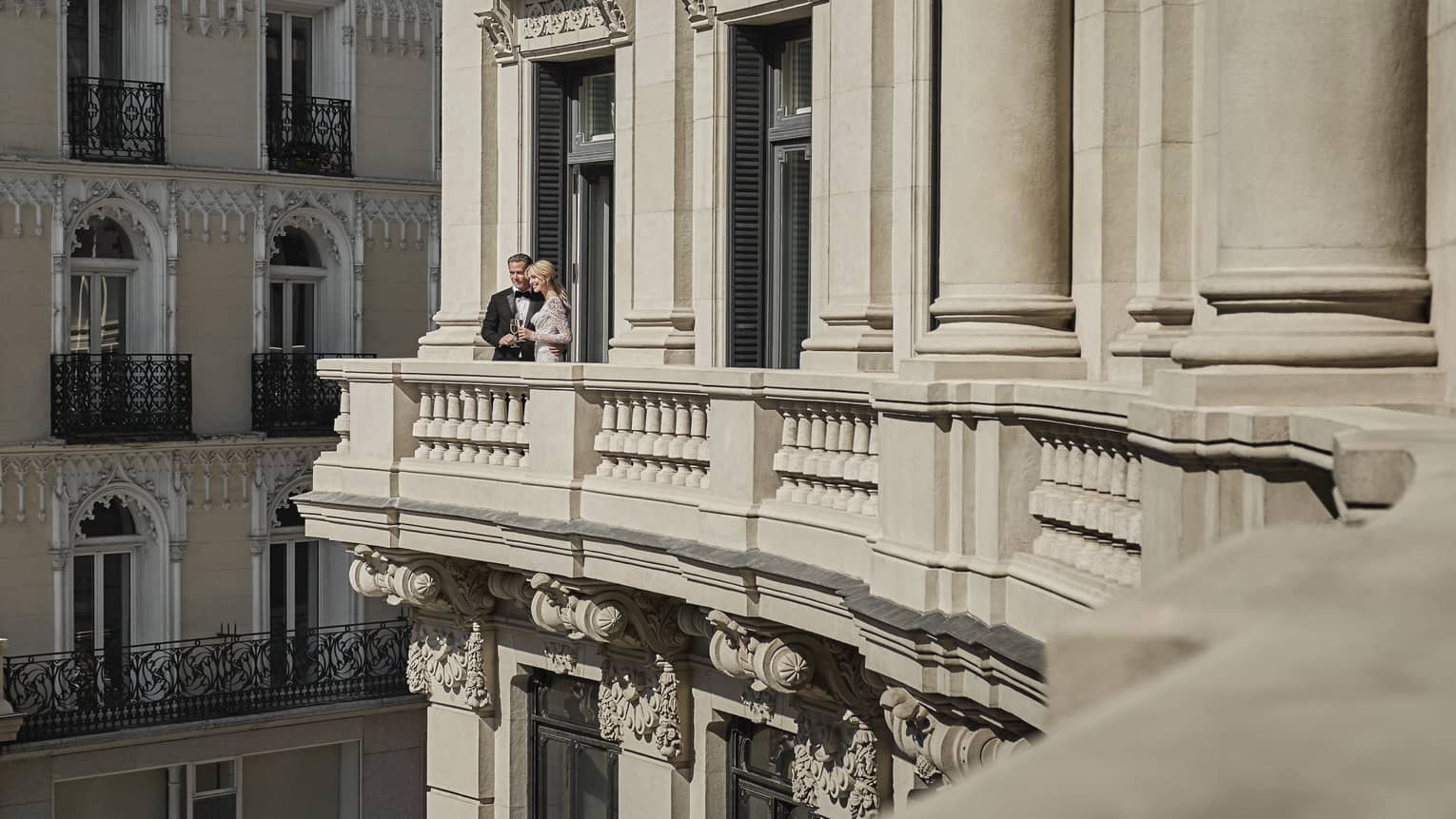 A wedding couple standing on the balcony of the hotel.