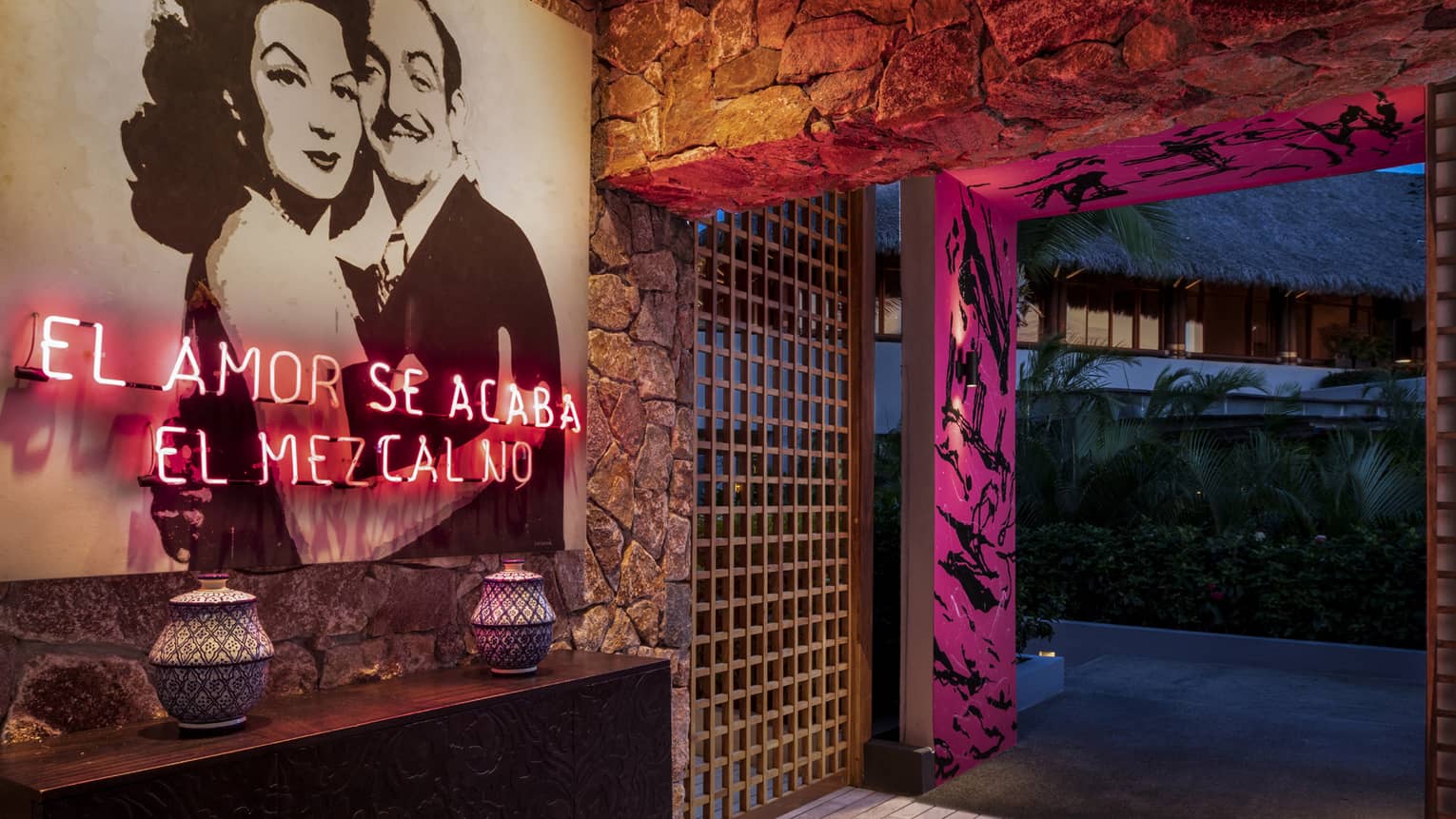 The interior entrance of a bar with a photo of a man and woman hugging and pink lighting.