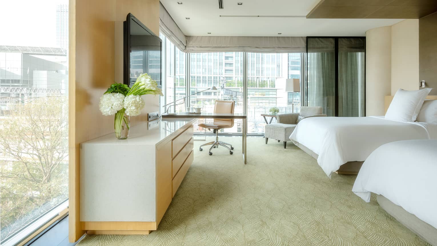 Deluxe Premier Twin Room with desk area and floor-to-ceiling corner windows looking out onto the city skyline