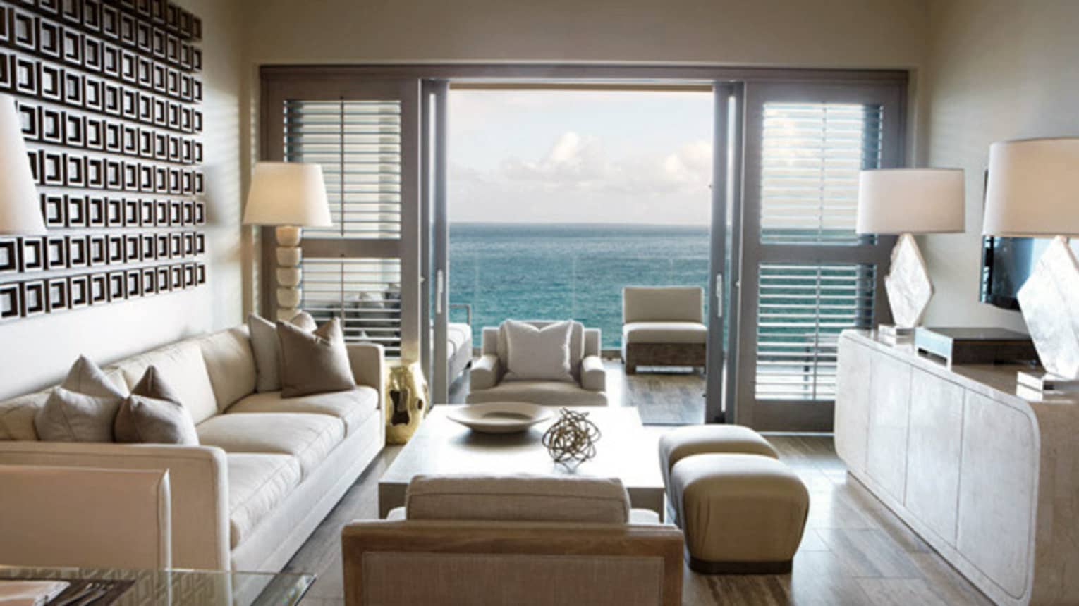 One-Bedroom Ocean-View Suite living room with white sofa and armchairs, patio door with ocean view